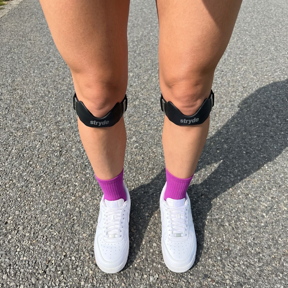 Deux Precision Strap portées sous les genoux avec des baskets blanches